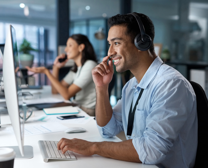 Shot Of A Young Man Using A Headset And Computer In A Modern Office
